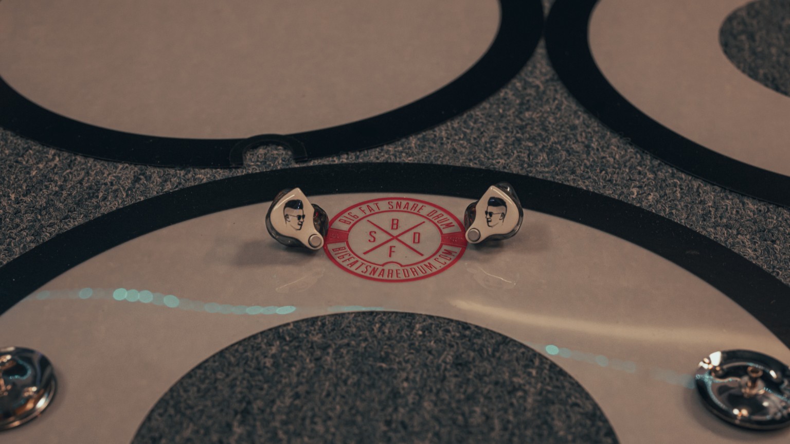 Kevin Michael Chong's custom 64 Audio in-ear monitors resting on a Big Fat Snare Drum accessory