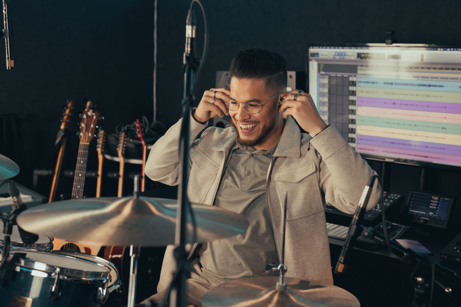 Kevin Michael Chong smiling while putting in his in-ear monitors during an Audix session