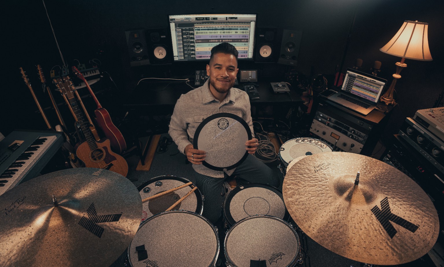 Kevin Michael Chong seated behind his kit holding a Big Fat Snare Drum accessory